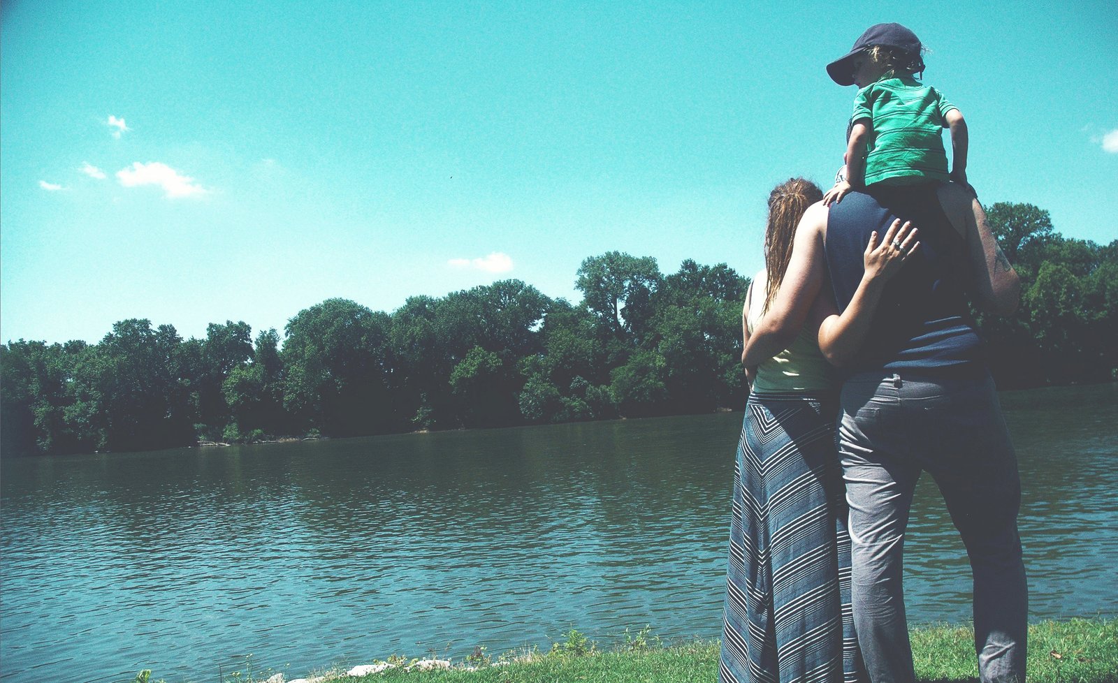 Young caucasian family of three looking out over a river