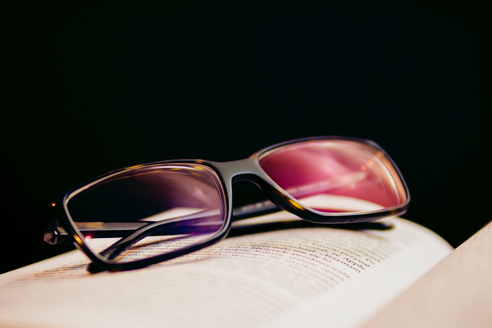 Reading glasses laying on top of open book