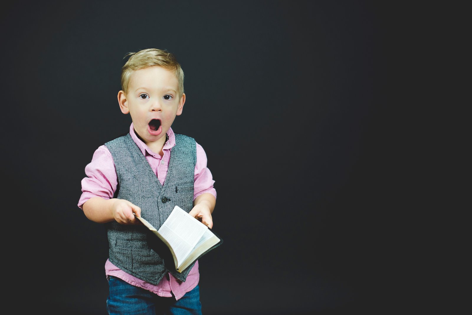 Caucasian toddler with surprised expression, holding a bible open