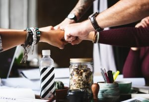At least five people have their fists together in a group fistbump